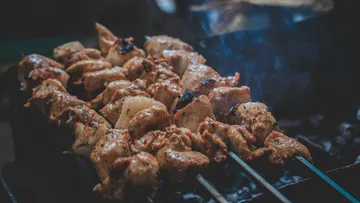Gegrillte Fleischspieße rosten über glühenden Kohlen im Freien.